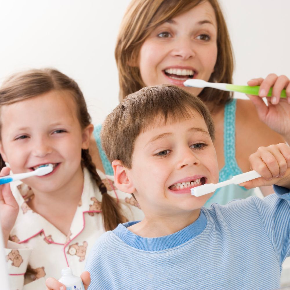 Kids brushing their teeth with Mom using manual toothbrushes