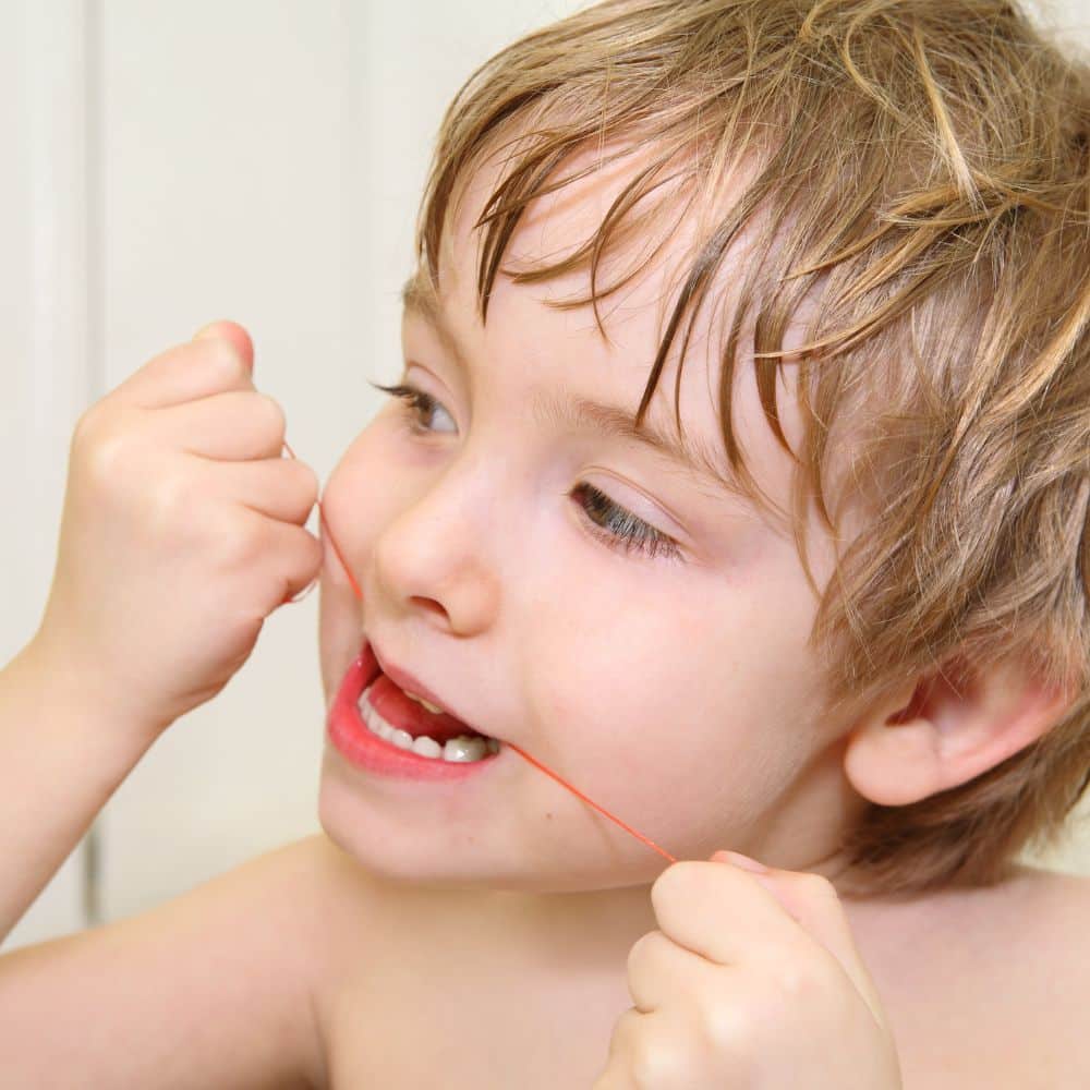 Young child flossing their teeth.